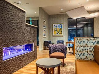 Cozy hotel lounge with modern furniture, a blue electric fireplace, and contemporary art on the walls